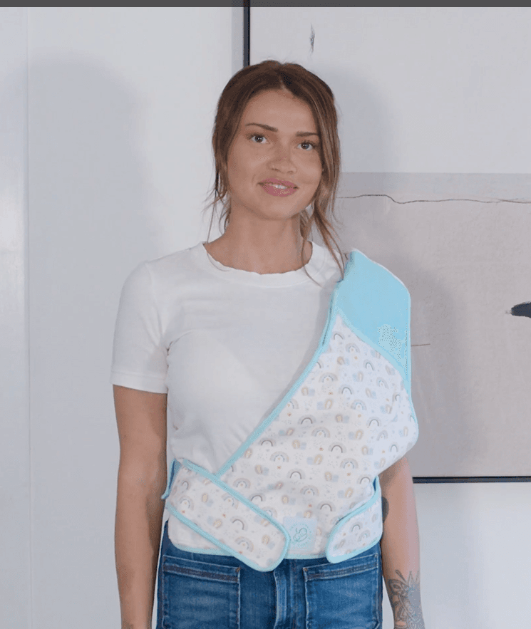 Parent wearing the Cool Cuddle sling with rainbow pattern